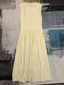 Détail d'une robe sans manches jaune clair avec taille haute large et jupe plissée fluide