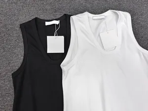 Detailed flat lay of high-quality black and white sleeveless vests on a grey carpet background