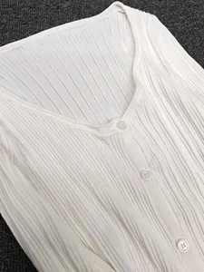 Close-up of ribbed knit texture and button detail on off-white long sleeve cardigan