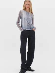 Detail of blue abstract print mesh long sleeve top paired with straight leg raw denim jeans