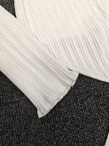 Close-up of ribbed texture and high-quality cuff stitching on white knit cardigan