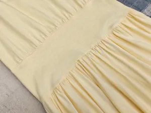 Gros plan sur la taille plissée d'une robe sans manches jaune pâle en coton doux