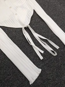 Detailed view of cream-colored knit cardigan with vertical ribbed texture and lace-up hem
