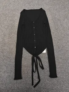 Detail of black ribbed knit cardigan with deep V-neck, buttons and tie-up hem