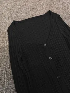 Detail of V-neck ribbed knit cardigan featuring front buttons on textured background
