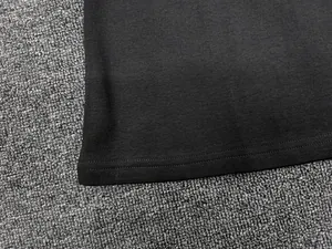 Close-up of double-needle hem stitching on black sleeveless cotton top vest