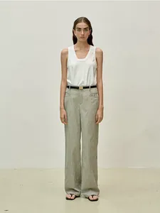 Detail of a white sleeveless U-neck vest paired with grey striped wide-leg trousers and belt