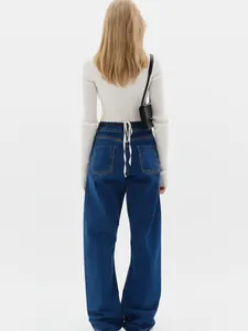 Detail of white ribbed knit cardigan featuring back tie detail and wide-leg denim jeans