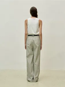 Detail of a white cotton sleeveless tank top styled with vertical striped trousers and belt