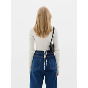 Back view of a white long sleeve ribbed knit cardigan paired with blue wide-leg jeans