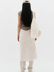 Back view of model wearing minimalist cream crossbody bag with adjustable wide strap