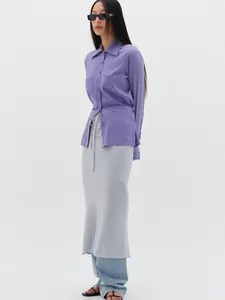 Detail view of purple drawstring shirt styled with layered midi skirt and denim