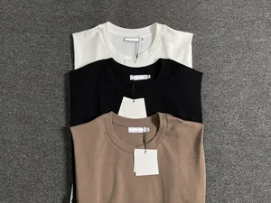 Flat lay detail of round neck cotton t-shirts in white, black, and coffee brown colors