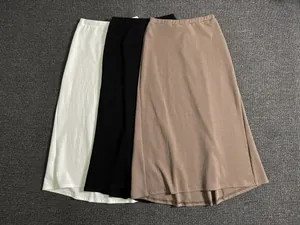 Flat lay detail of elastic high waist long A-line skirts in white, black and khaki
