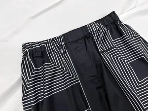Detail of elastic waistband and geometric print on black loose trousers for women
