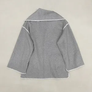Detail of wool coat showing white zigzag hand-stitched embroidery on light grey lapel
