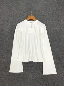 Detail view of white long sleeve top with flared cuffs and round neck on a hanger