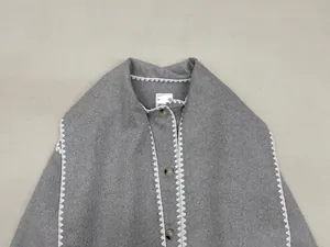 Close-up of grey wool vest with white zigzag stitching and marble textured buttons