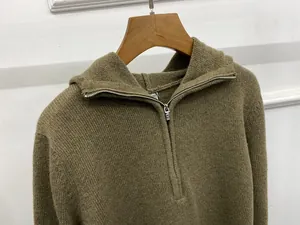 Detailed close-up of a brown knit hoodie featuring a half-zip metal zipper and ribbed texture