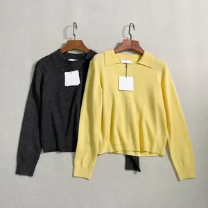 Detailed view of polo collar knit sweaters in grey and yellow with brand tags