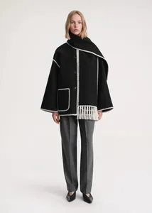 Detail of black wool coat featuring white contrast stitching and a matching fringed scarf