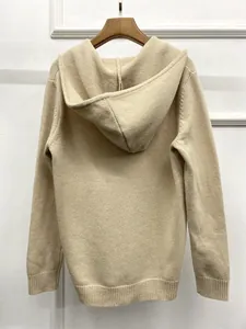 Close-up of minimalist beige hooded knit sweater with ribbed cuffs and wooden hanger