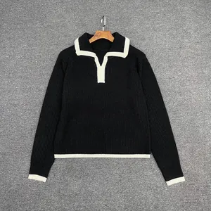Close-up of thick rib-knit texture and white contrast piping on a black polo sweater