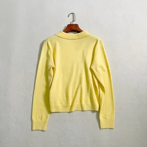 Detailed view of yellow long sleeve knit polo shirt featuring soft texture and ribbed cuffs