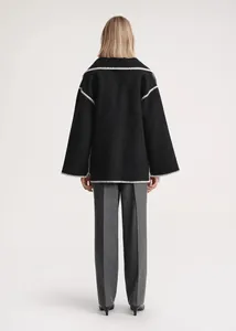 Back view of a black wool short coat with white contrast stitching and matching scarf