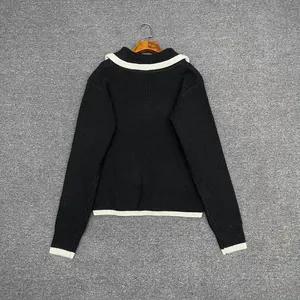 Detail view of the black knit sweater back with contrasting white stripe trim on the hem