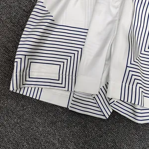 Detailed view of geometric navy print on white woven fabric with precision stitching