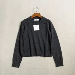 Detail view of charcoal grey knit polo sweater with ribbed hem on a wooden hanger
