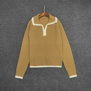 Close-up of mustard yellow ribbed knit sweater with white contrast trim and polo collar