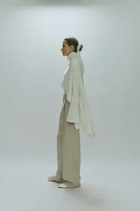 Detail of white high-neck poncho top featuring delicate lace embroidery on the back neck