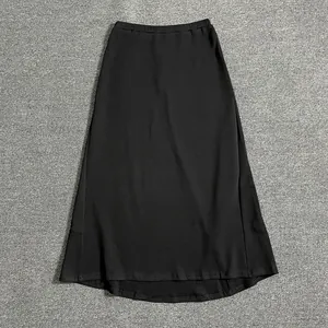 Close-up of black A-line maxi skirt with elastic waistband on grey textured carpet