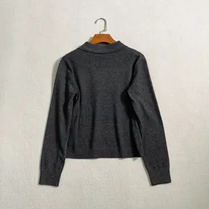 Detail view of the back of a dark grey knit polo shirt with ribbed cuffs and hemline