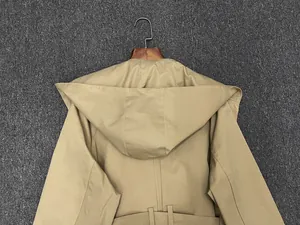 Back view of a khaki hooded trench coat with belt loops hanging on a wooden hanger
