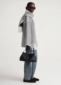 Detail of grey wool coat featuring white fringe trim and elegant wavy contrast stitching