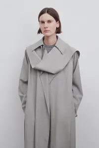 Détail d'un long trench-coat gris montrant le col écharpe drapé superposé unique