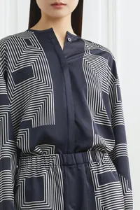 Detailed close-up of navy silk shirt with white geometric patterns and stand collar