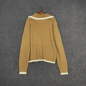 Macro view of mustard yellow knit sweater showing ribbed texture and white contrast piping