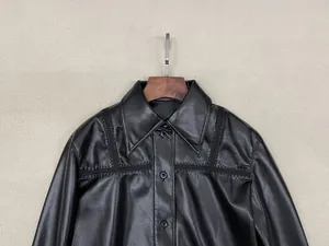 Detail of black leather shirt showing pointed collar and refined stitching texture