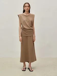Detail of two-piece dark camel knit set with padded shoulder vest and maxi skirt