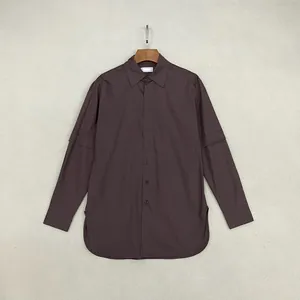 Dettaglio camicia in cotone marrone scuro con colletto a punta e maniche con pieghe