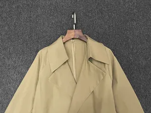Detailed macro view of khaki trench coat wide lapel and button with wooden hanger