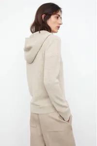 Detail of oatmeal knit hoodie texture and premium soft wool blend fabric on a woman
