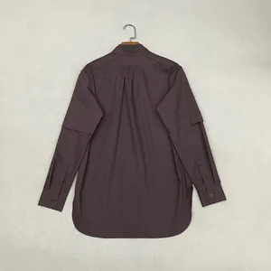 Dettaglio camicia in cotone viola con pieghe posteriori e polsini delle maniche a strati