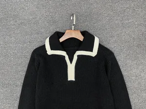 Detail of loose long-sleeve knit sweater featuring a black and white contrast polo collar