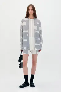 Detail of white long-sleeved shirt with black geometric pattern and matching shorts