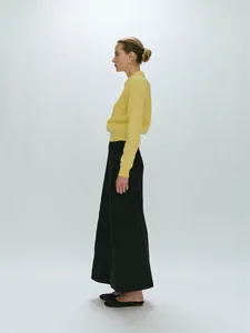 Detail view of premium knit polo shirt in soft yellow with elegant black maxi skirt